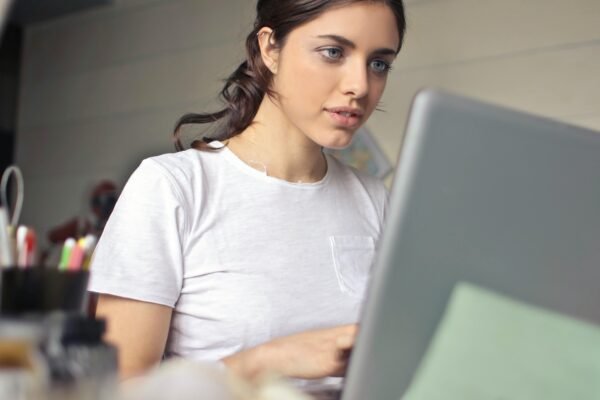 Young woman attentively working on her laptop in a cozy indoor setting.